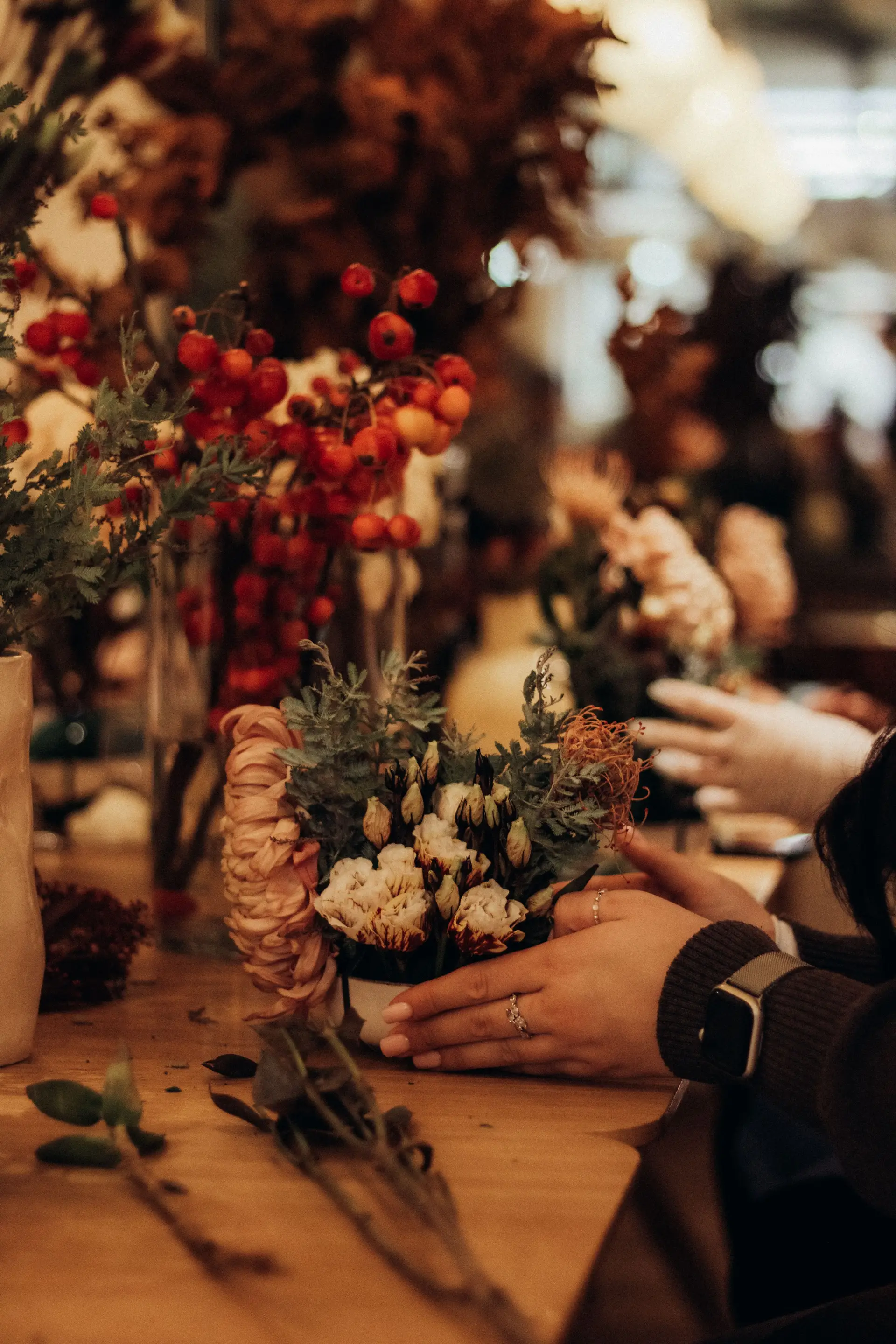 Hands crafting a floral display in a warm studio setting